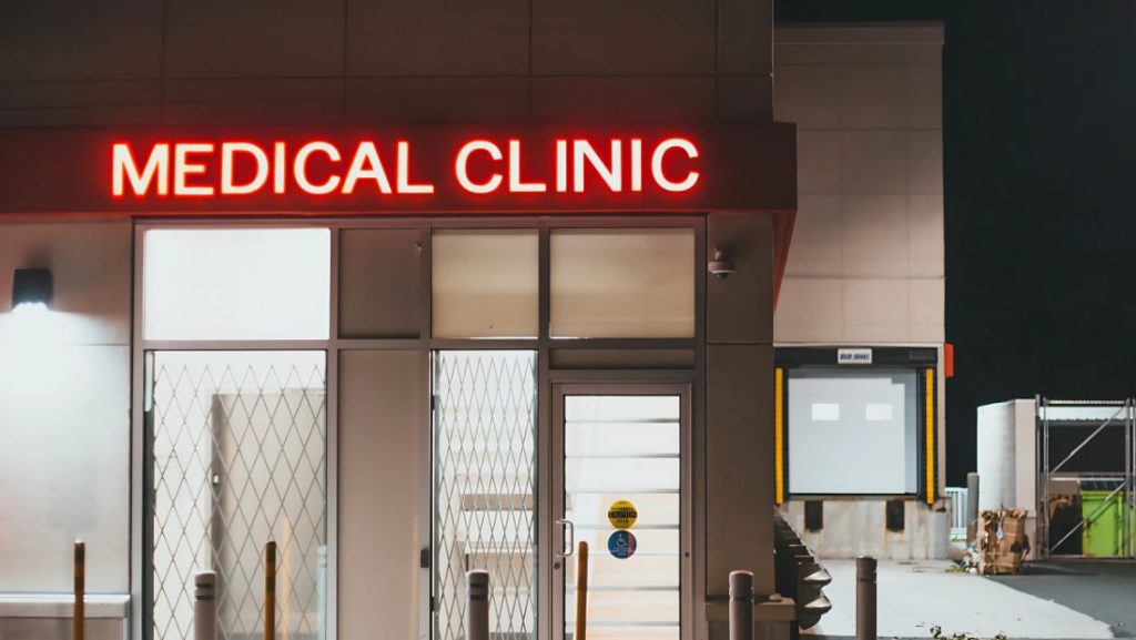 Exterior of a medical clinic at night with a bright red LED signage that reads 'MEDICAL CLINIC' above the entrance.