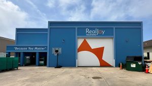 RealJoy Vacations branding integrated into a blue commercial building with a large orange wall graphic.