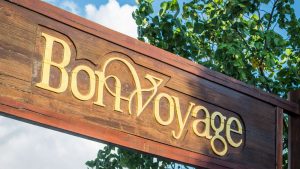Wooden Bon Voyage sign with dimensional gold lettering, a classic example of elegant Retail Store Display Signs used for branding and wayfinding.