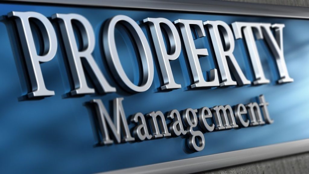 Close-up of a professional "Property Management" building sign with raised letters on a blue background, created by a signage company near me.