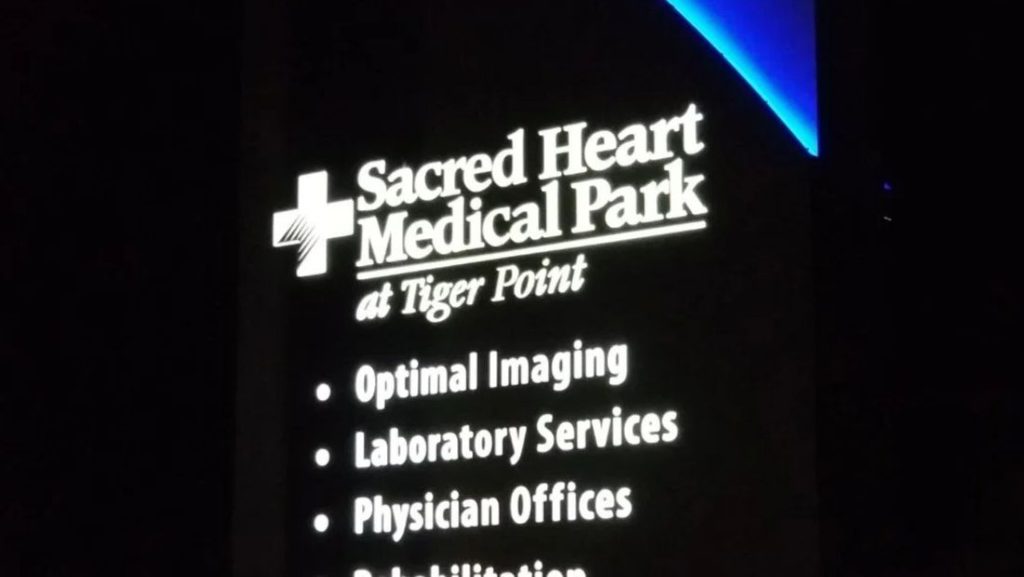 LED monument sign Lutz FL displaying Sacred Heart Medical Park at Tiger Point with listed services including imaging, laboratory, physician offices, and rehabilitation.