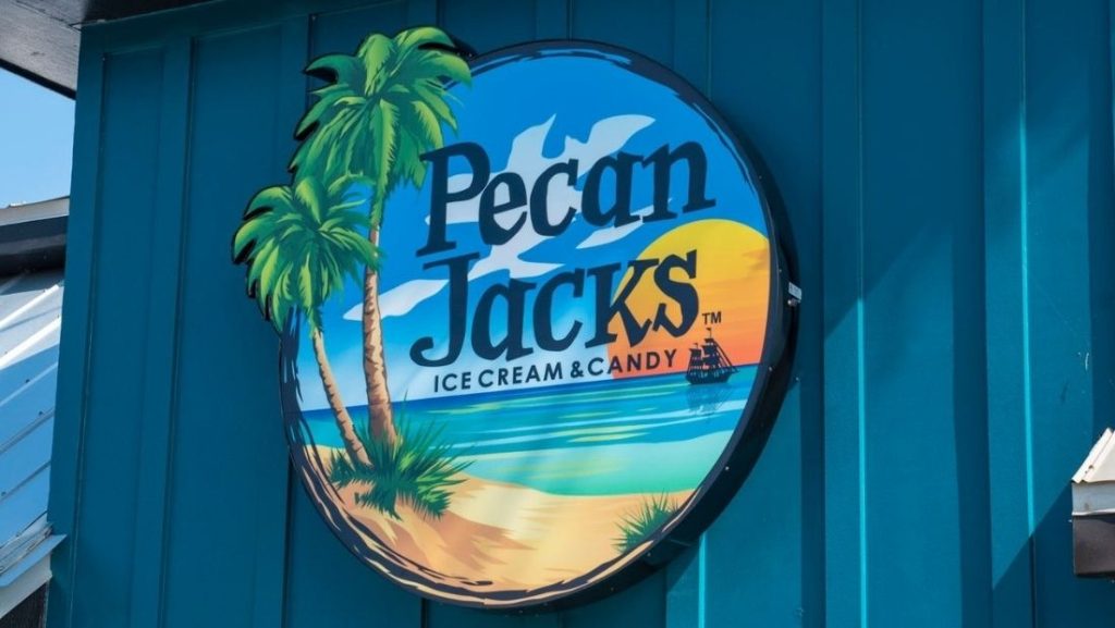 Sign for Pecan Jacks Ice Cream & Candy with a beach scene and palm trees in the background.