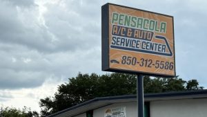 A large outdoor sign for Pensacola A/C & Auto Service Center with the business name and contact number displayed. Sign installation services provided by a local company.