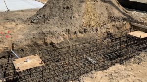 A construction site showing the foundation being prepared for a sign installation, with rebar structures in place for support. Sign installation services in progress.