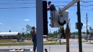 Technicians working on a roadside sign using a bucket truck during a daytime install, illustrating factors that influence commercial sign installation cost.