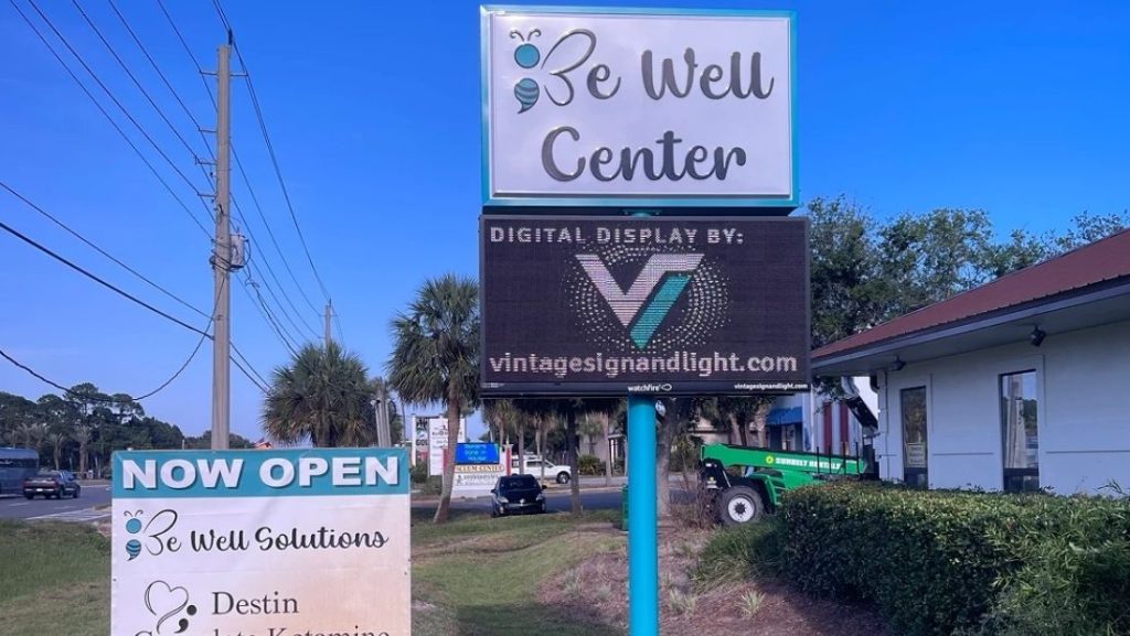 Digital signage installation at Be Well Center, featuring a vibrant digital display showcasing the business logo and branding, with the 'Digital Display by VintageSignandLight.com' text visible.