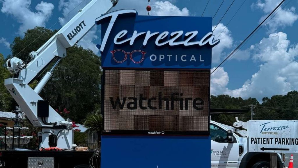 Outdoor commercial digital signage display at Terrezza Optical, showcasing a Watchfire screen with a truck and crane in the background.