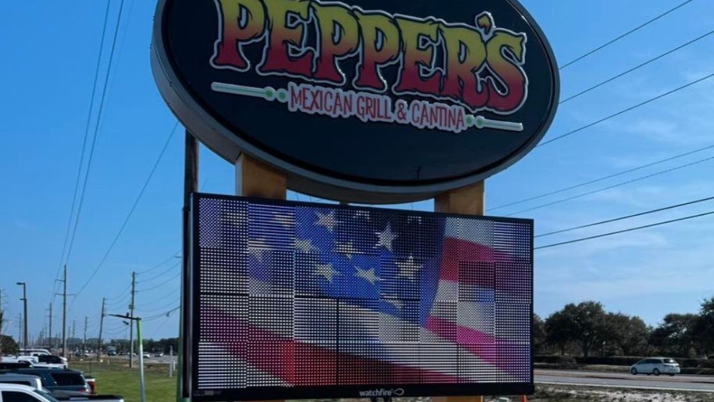 Digital wayfinding signage outside Pepper's Mexican Grill & Cantina, displaying an American flag on a vibrant LED screen. The sign provides an eye-catching visual display to attract attention and inform passersby