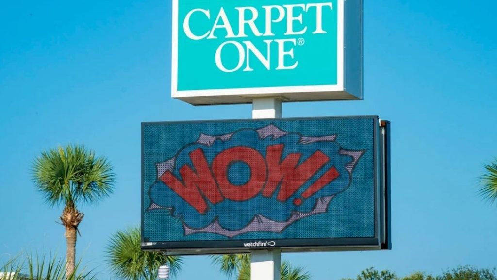 Retail digital signage display showing the word 'WOW!' in bold, eye-catching colors and comic-style text on an LED screen outside a store.