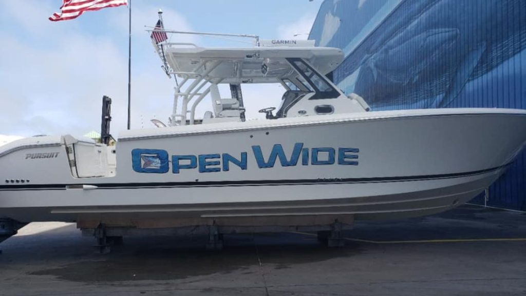 Custom boat lettering displaying the “Open Wide” logo on the side of a white center-console fishing boat with clean vinyl graphics.