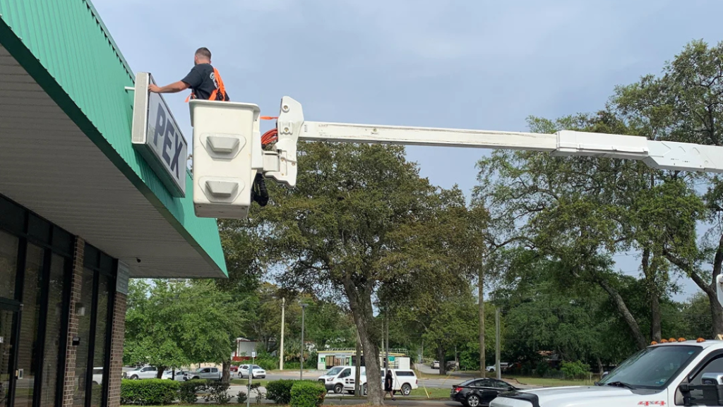 Sign installer using a bucket lift to install a PEX storefront sign.