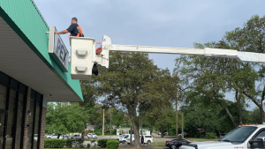 Sign installer using a bucket lift to install a PEX storefront sign.