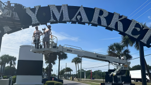 Sign installers working from a boom lift on a large elevated commercial sign.
