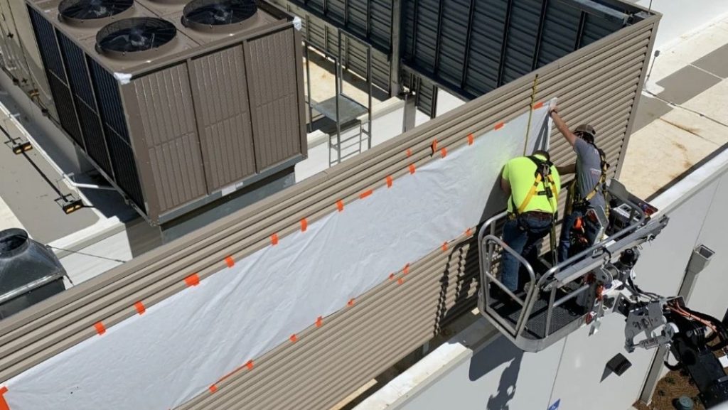 A professional sign installer uses a lift to mount a sign on a building, showcasing how professional sign installation works.