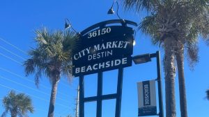 Tall pylon sign for City Market Destin Beachside near palm trees, showing how commercial zoning restrictions influence sign height, lighting, and roadside visibility.