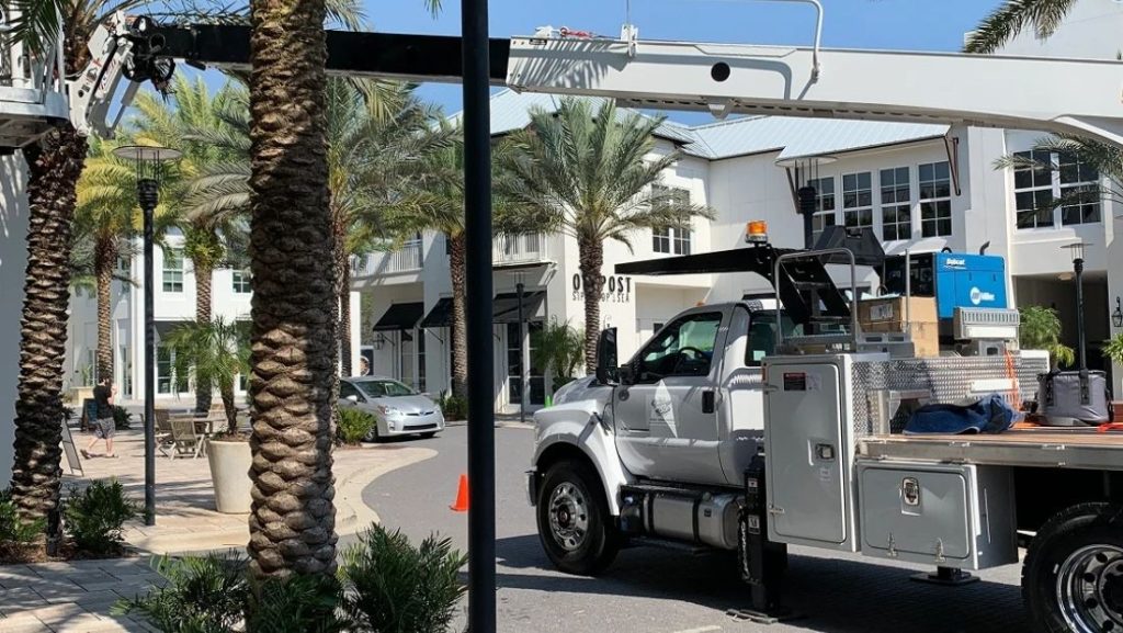 what is a signage permit illustrated by a commercial sign installation truck and boom lift preparing to install signage outside a retail building in Florida