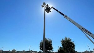 what is a signage permit illustrated by technicians using a boom lift to install or service a tall commercial sign pole in a retail parking area