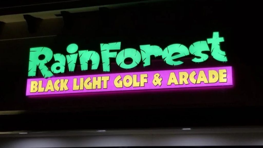 How are channel letters made: colorful illuminated channel letters sign for Rainforest Black Light Golf & Arcade with bright LED lighting on a commercial building at night