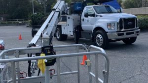 White bucket truck and lift equipment parked on-site with safety cones and organized sign installation tools prepared for commercial sign installation work.