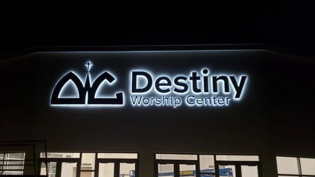 Illuminated channel letter sign for Destiny Worship Center mounted on the exterior of a church building at night