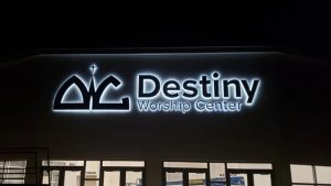 Illuminated channel letter sign for Destiny Worship Center mounted on the exterior of a church building at night