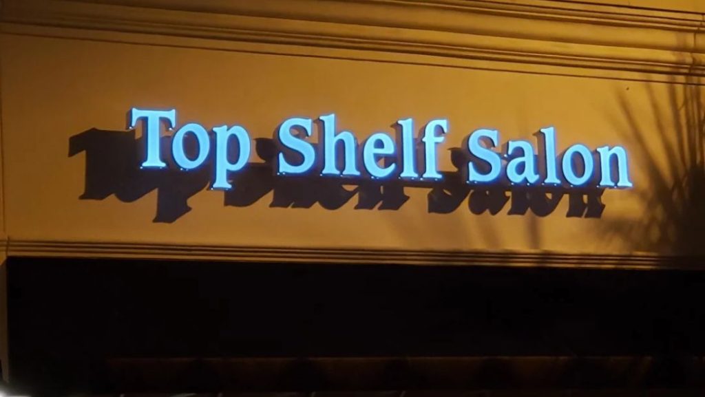 Illuminated Top Shelf Salon channel letter sign mounted on a storefront at night by Vintage Sign & Light