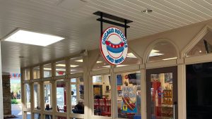 Hanging Chicago Hotdogs and More sign above a restaurant entrance in a covered walkway.