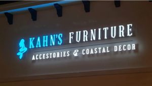 Illuminated Kahn’s Furniture channel letter sign on an exterior storefront wall at night.