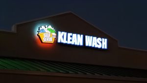 Illuminated Klean Wash channel letter sign mounted high on a building at night.
