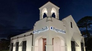 Illuminated Progress Bank channel letter signs installed on a commercial building at night.