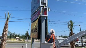 Vintage Sign & Light installer working from a lift beside a roadside digital sign.