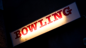 Illuminated bowling cabinet sign with uneven lighting across the sign face.