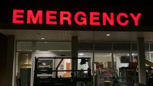 Illuminated red emergency channel letters above a hospital entrance at night.