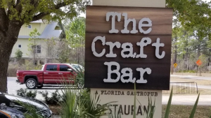 Wooden monument sign for The Craft Bar, a Florida gastropub in Destin, FL, with raised white lettering.