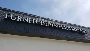Channel letters mounted on a dark metal panel storefront.