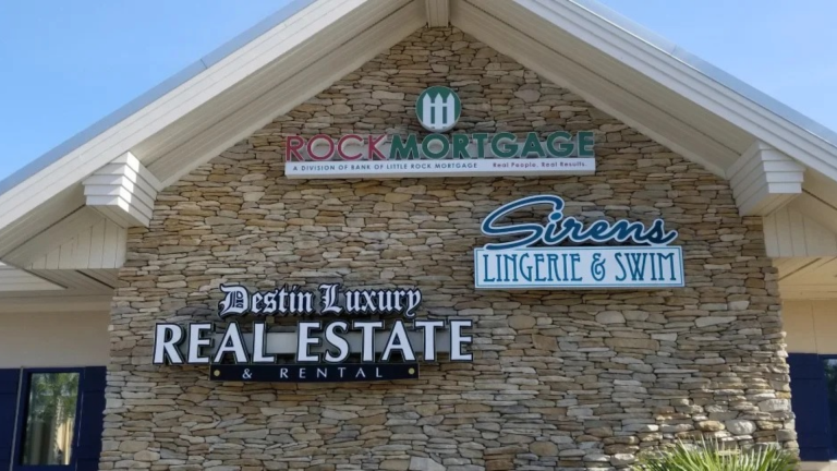 Multiple commercial signs mounted on a stacked-stone building façade.