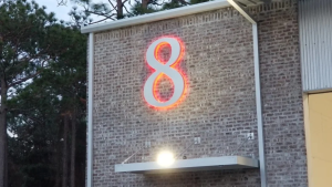 Illuminated wall sign mounted on a brick commercial façade.
